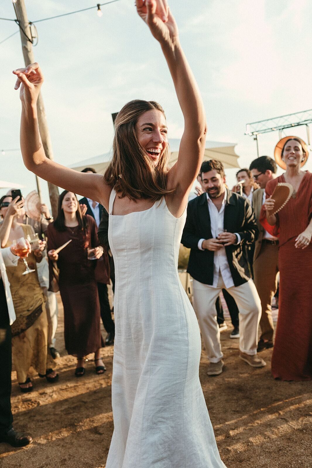 Una novia bailando con los brazos en alto entre los invitados