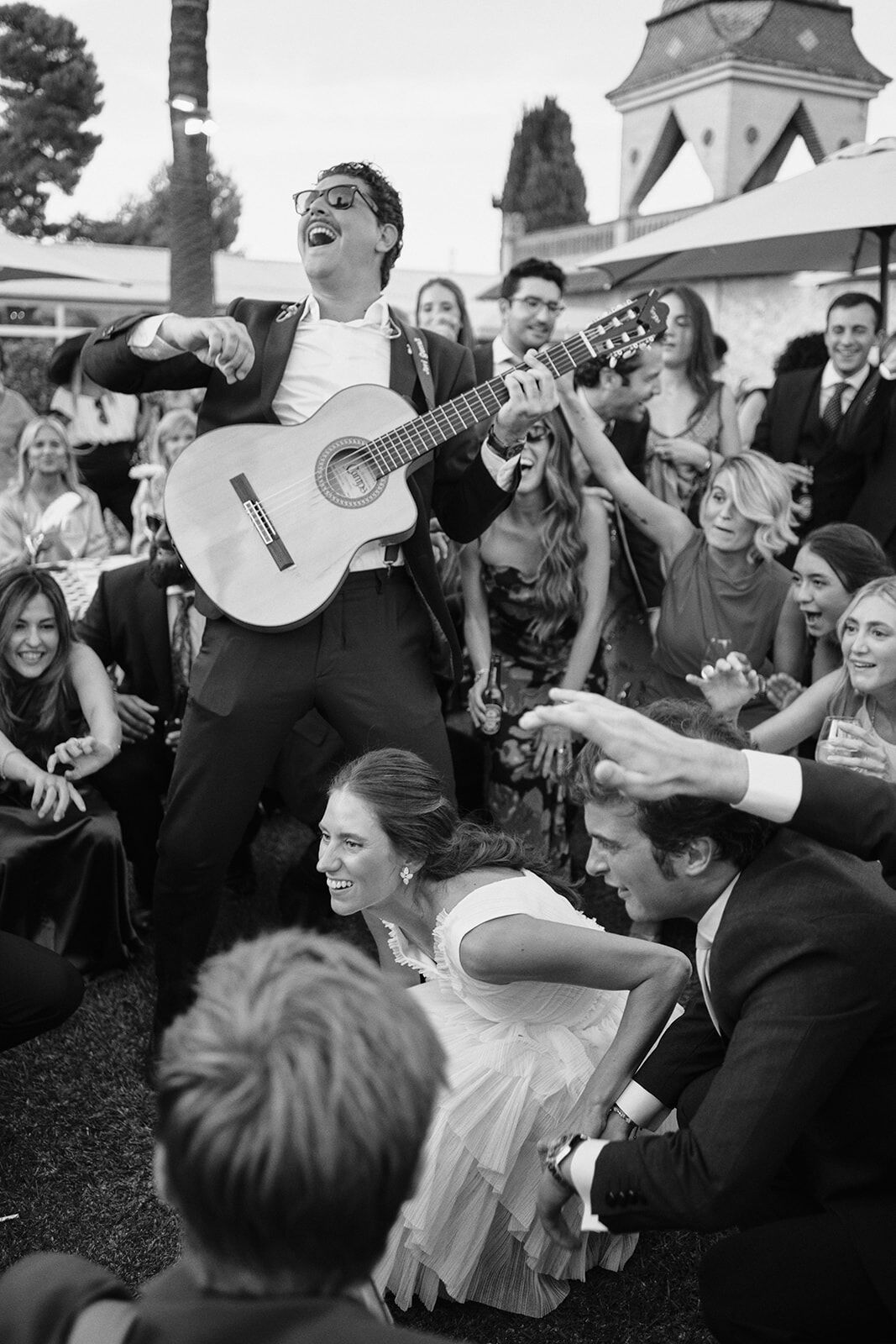 Guitarrista cantando entre los invitados mientras la novia baila agachada
